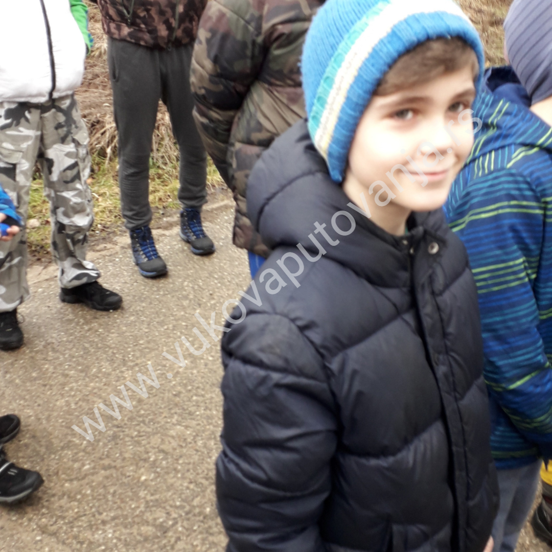 Post Vodopad ljubavi/fotka 3 Nasmejani dečak sa plavom kapom i teget jaknom stoji sa drugarima